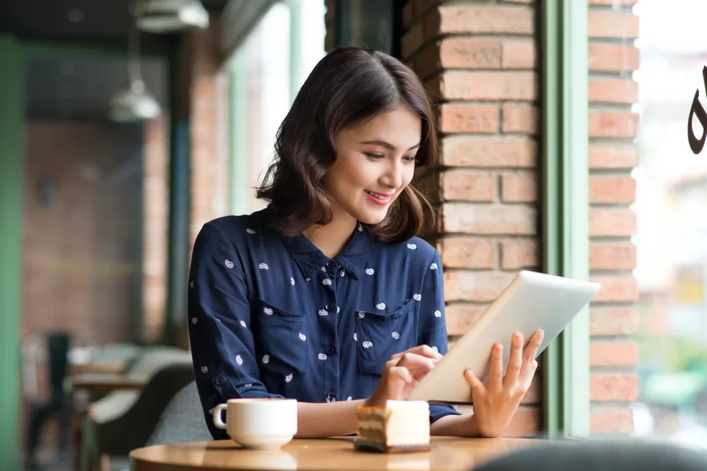 A young woman on her tablet and drinking coffee